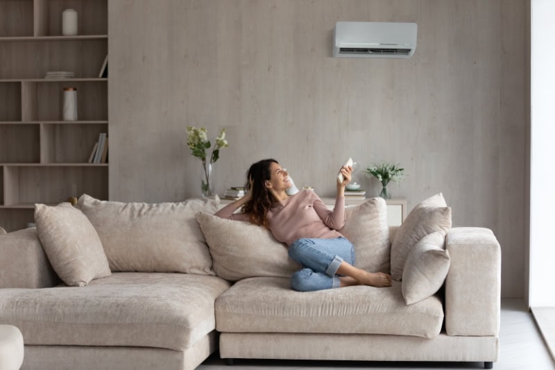 Relaxed young female homeowner sitting on huge comfortable couch.