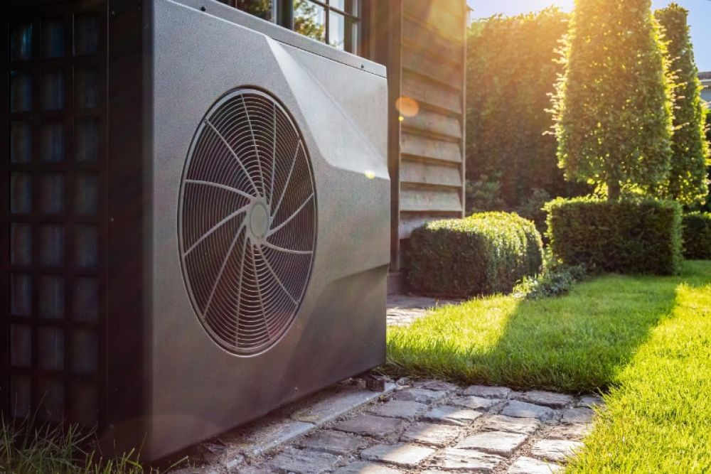 Outdoor heat pump beside a house on a sunny day, highlighting energy-efficient heating and cooling technology.