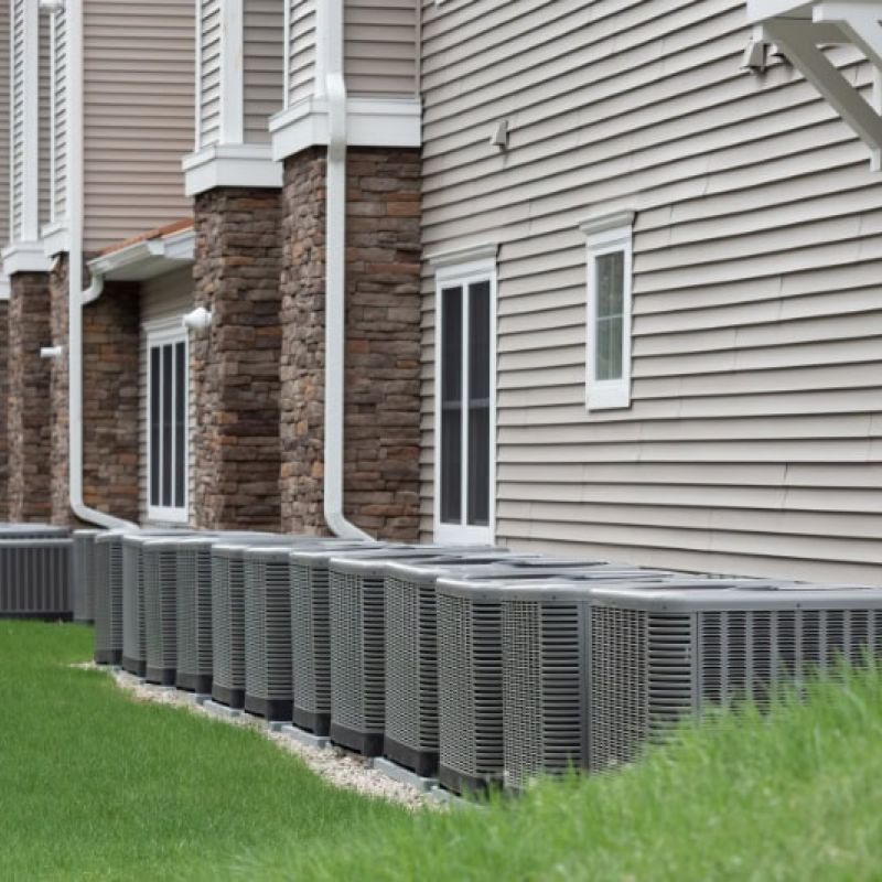 Row of outdoor air conditioning units lined up against residential building for cooling efficiency.