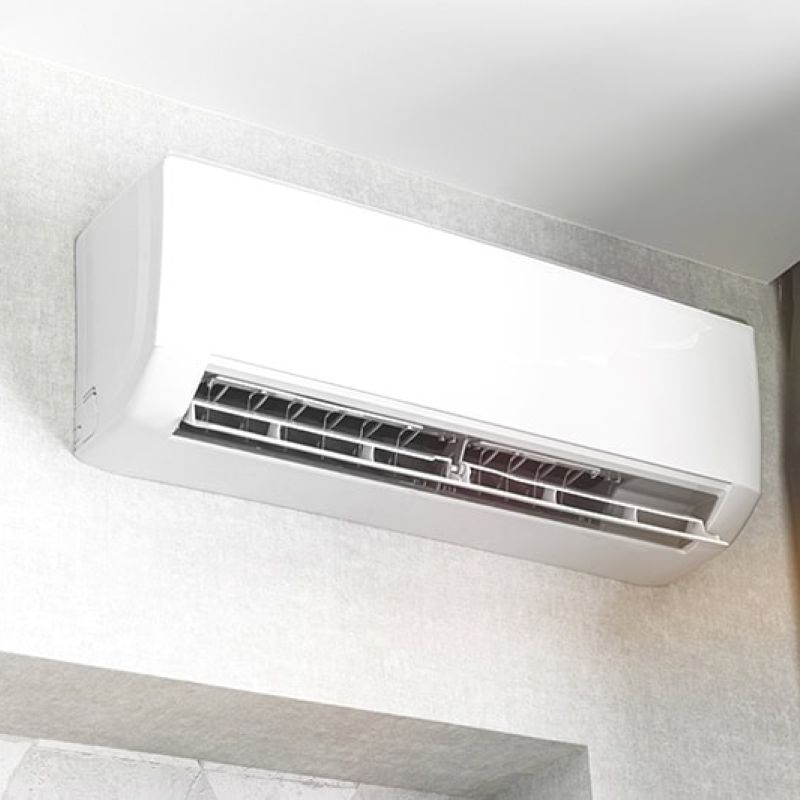 Wall-mounted air conditioning unit in modern room with gray curtains and minimalist decor.