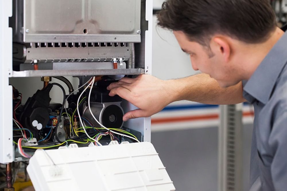 Technician repairing a boiler, adjusting internal components and wiring for optimal performance and safety.