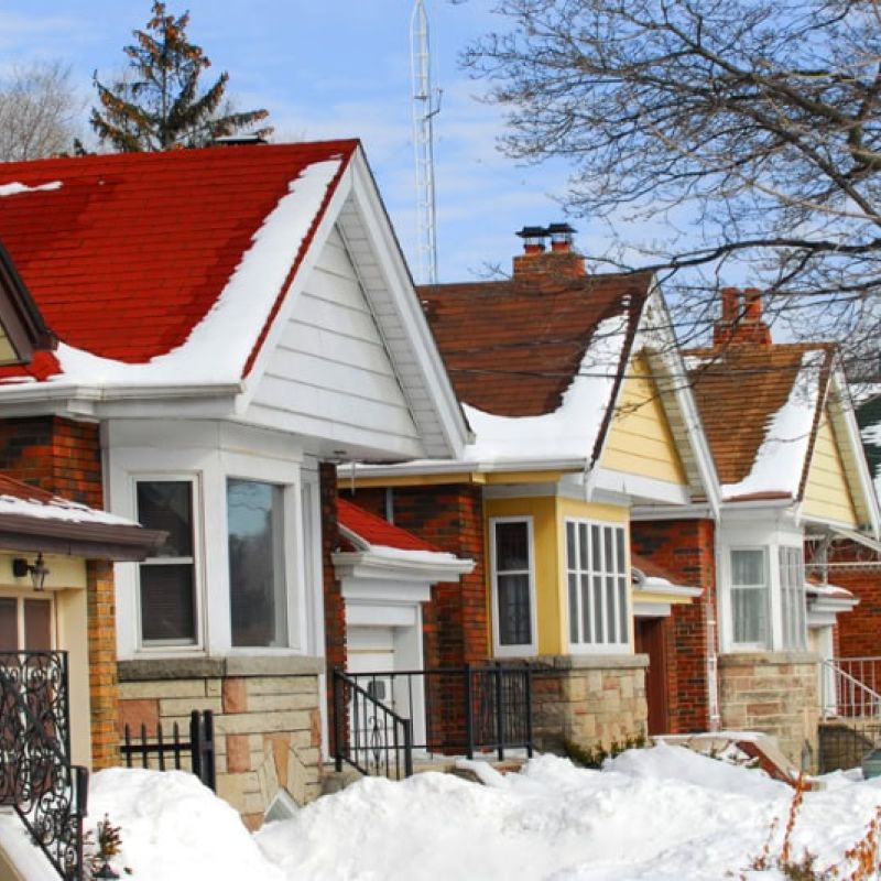 Row of charming snow-covered brick houses with colorful roofs in winter.