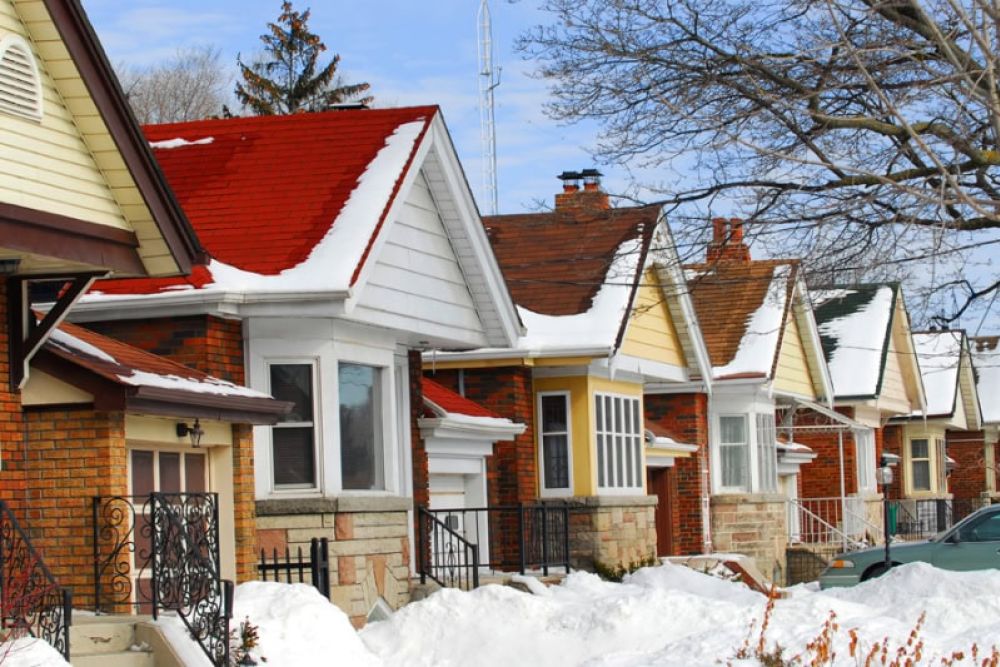 Row of charming snow-covered brick houses with colorful roofs in winter.